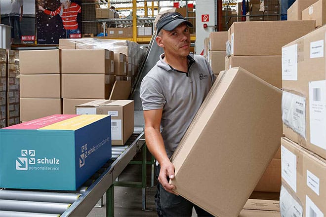 Mitarbeiter stapelt Kartons